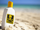 A red danger sign showing the toxic sunscreen recall warning on a sunny beach