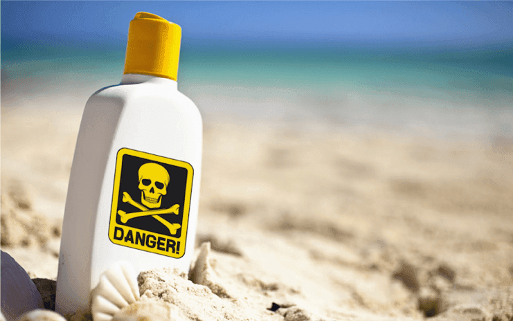 A red danger sign showing the toxic sunscreen recall warning on a sunny beach
