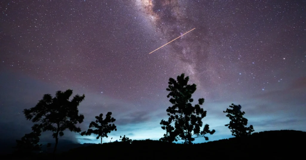 A bright meteor streaking across the dark starry night sky