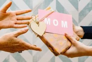 A person holding a phone showing a fake Mother's Day scam message
