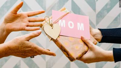 A person holding a phone showing a fake Mother's Day scam message