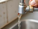 A close up of a faucet showing the dangerous tap water alert in a home