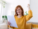 A happy woman holding an energy bill grant letter and saving money