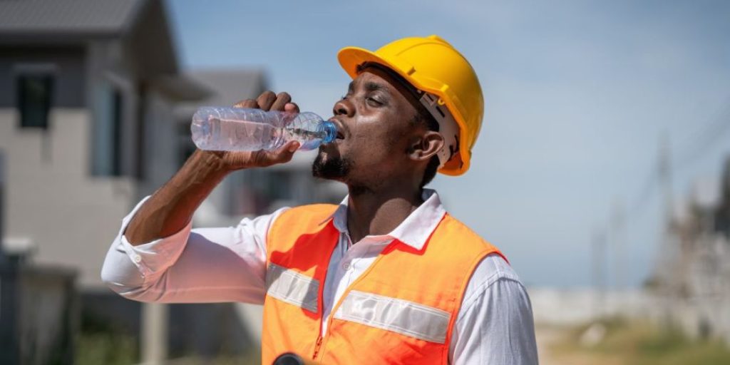 An outdoor worker drinking water during the severe Kansas City heat advisory today